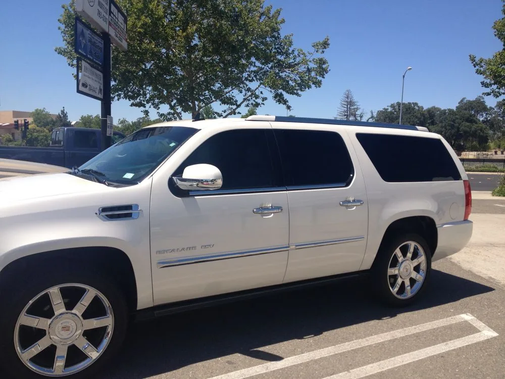 White SUV with tinted windows parked in lot with trees and signage visible
