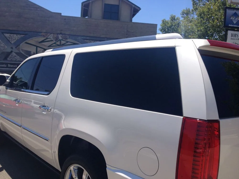 White SUV with tinted windows and red taillights parked on street near building