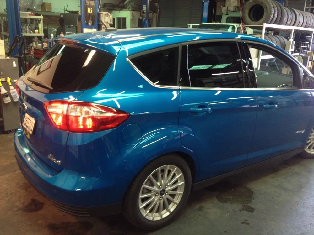 Blue compact car parked in auto service garage with equipment visible in background