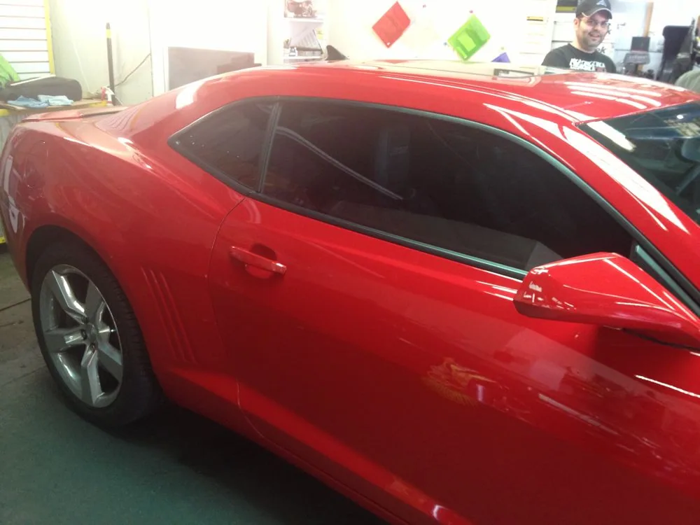 Red sports car with tinted windows in an indoor garage or showroom setting