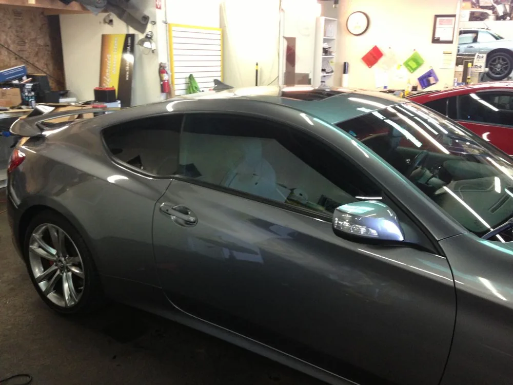 Gray coupe parked in auto shop with tinted windows and alloy wheels