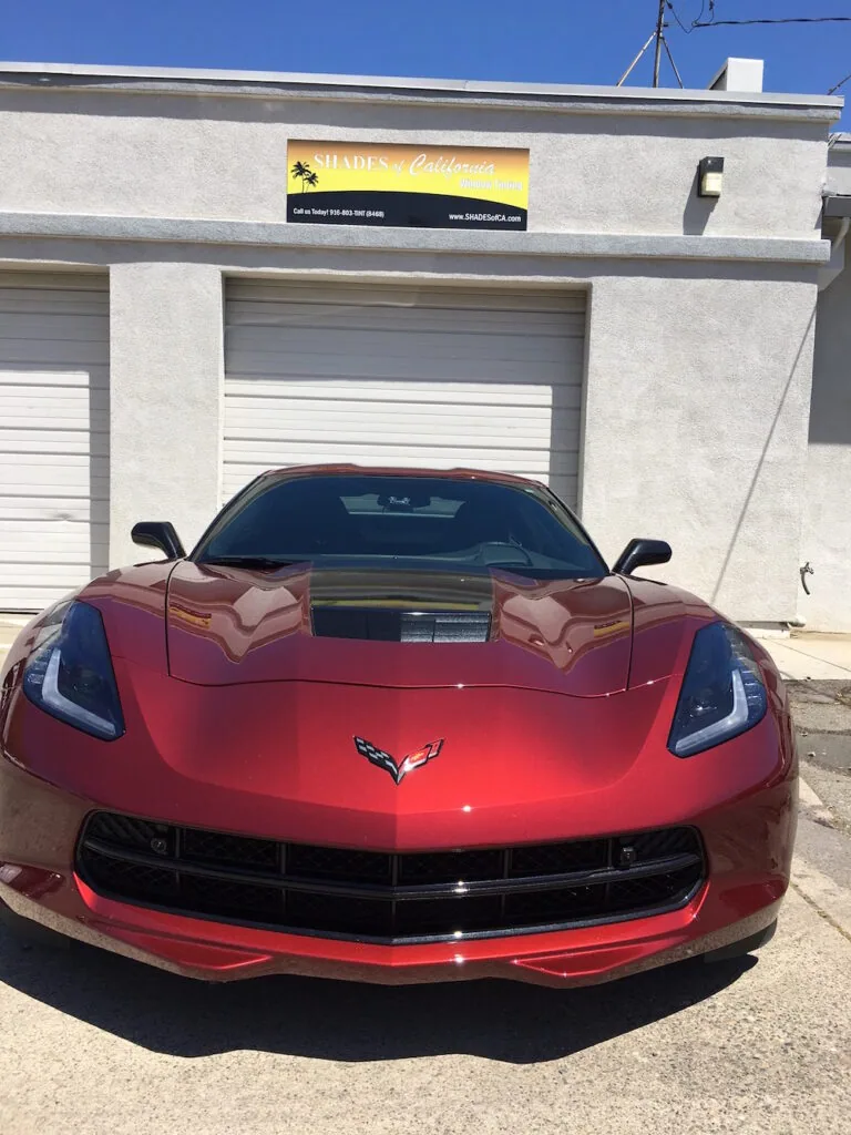 Red sports car parked in front of white garage doors on concrete building