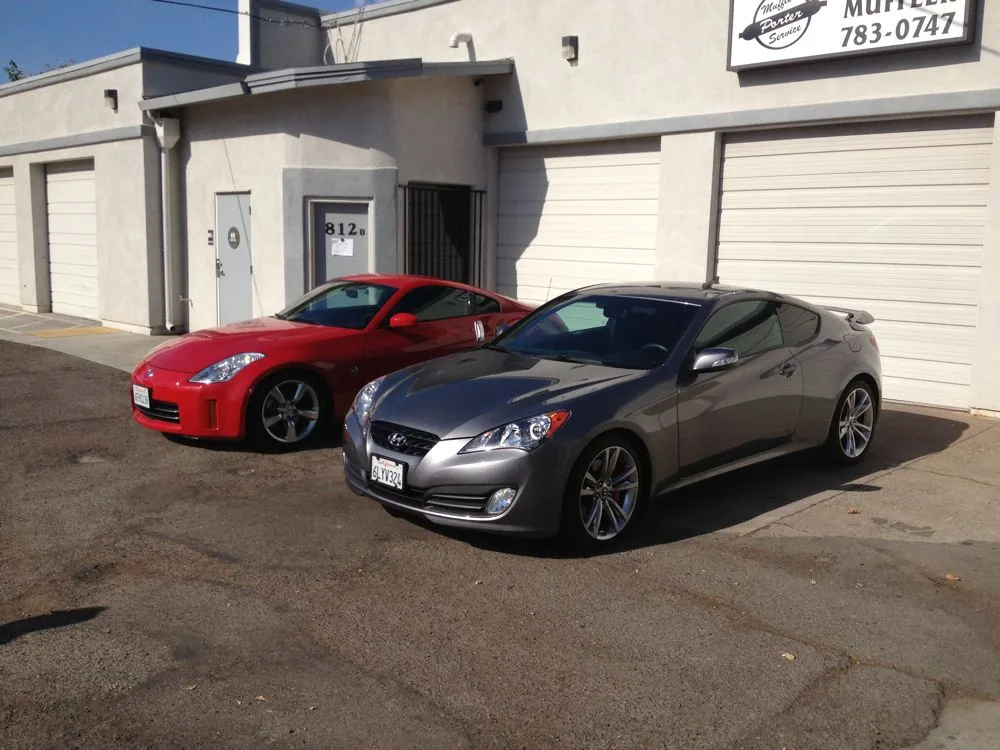 Red and silver sports coupes parked in front of a commercial building with garage doors