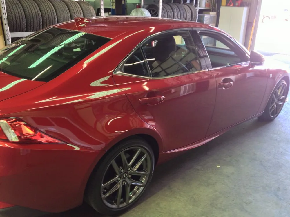Red sedan with tinted windows parked in a tire shop garage