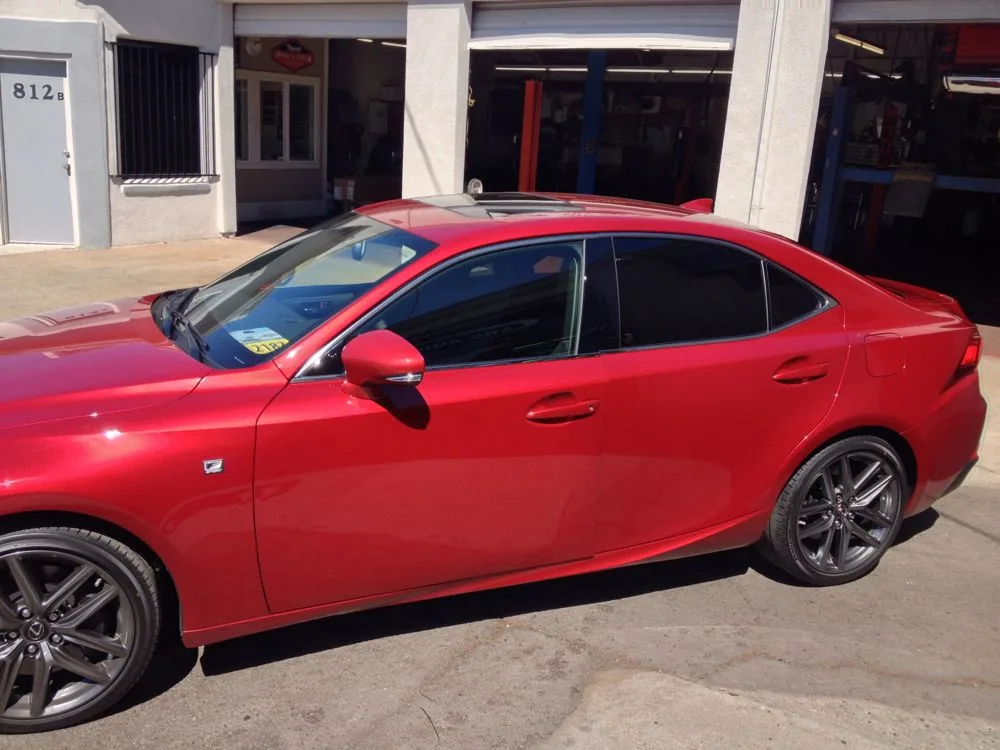 Red sedan with tinted windows parked in front of storefront
