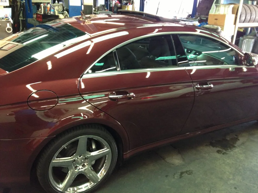 Burgundy sedan with tinted windows in an auto shop with chrome wheels visible