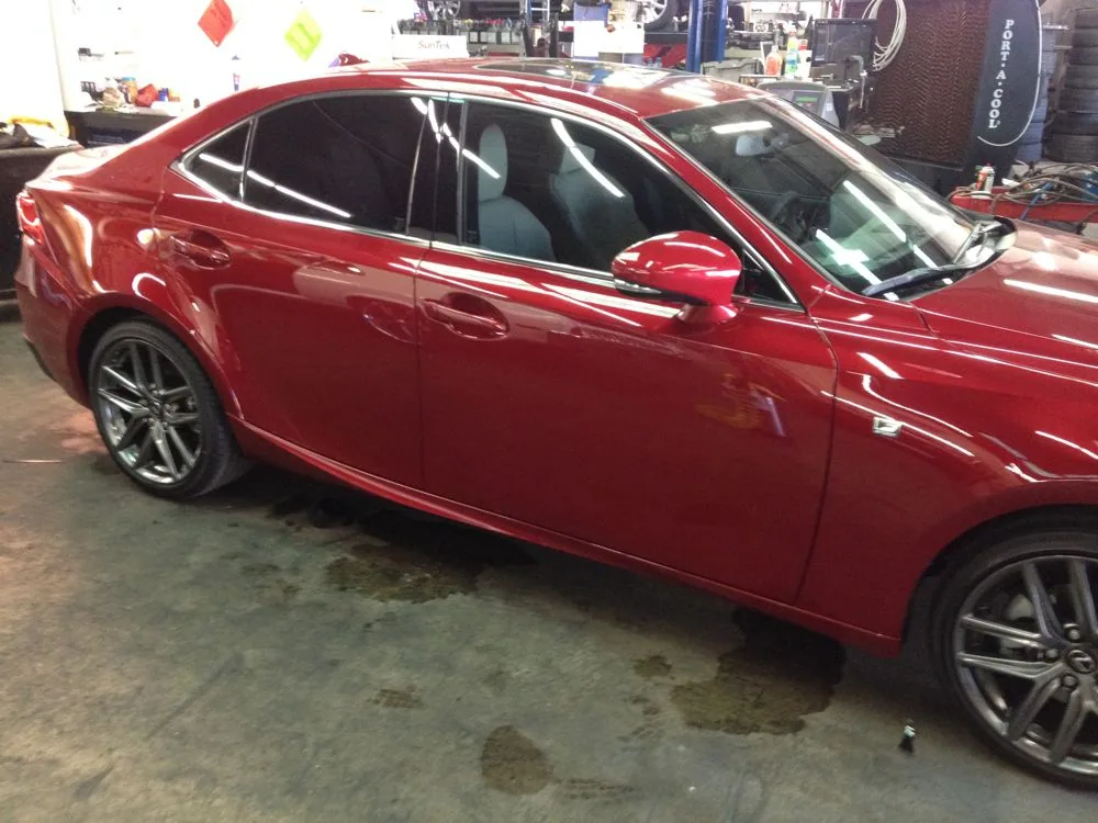 Red sedan with tinted windows parked in a auto shop garage