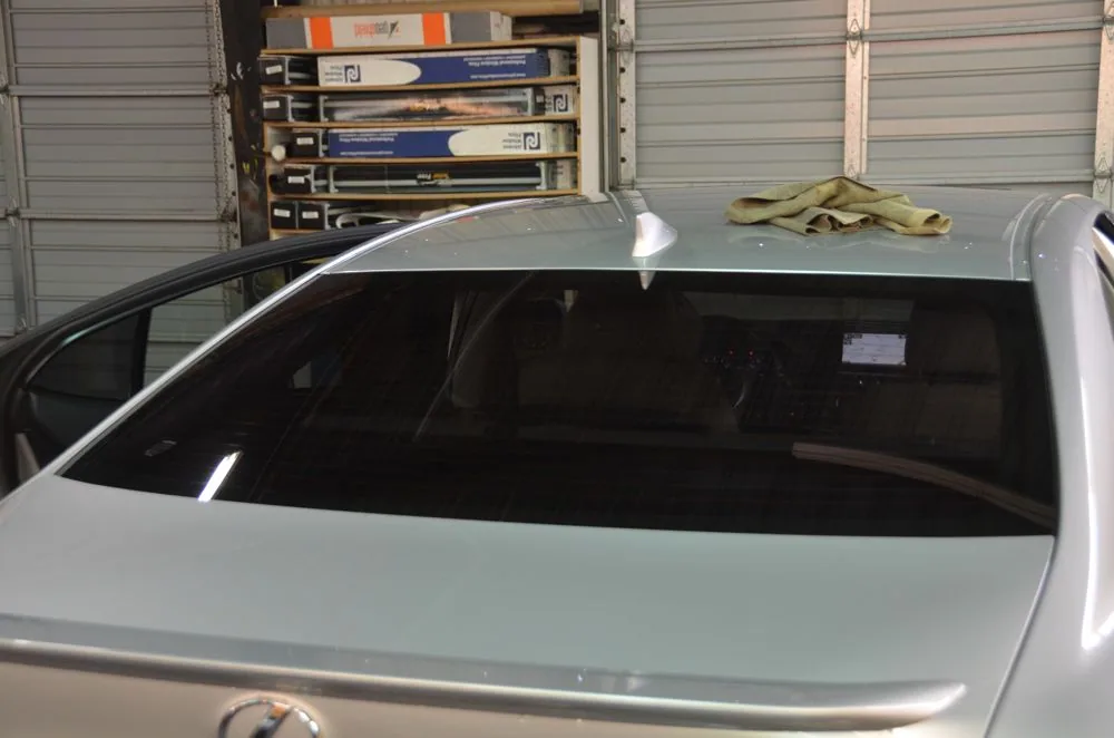 White sedan with tinted rear window parked in garage with storage shelves and boxes in background