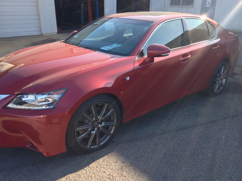 Red sedan parked in driveway with tinted windows and alloy wheels