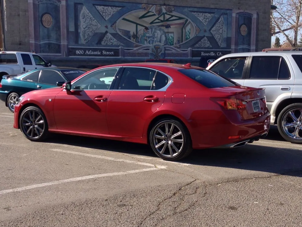 Red sedan parked in lot with other vehicles and decorated building facade in background